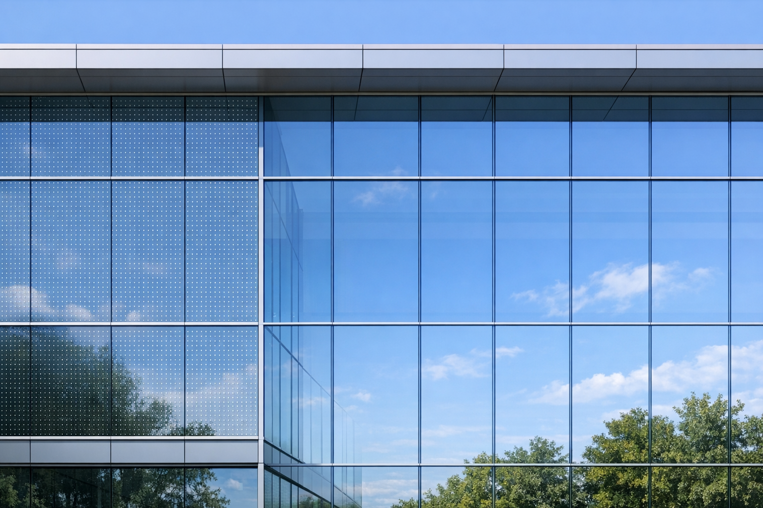 Modern glass curtain wall reflecting sky and trees, with a subtle dot pattern visible on part of the façade to indicate bird‑friendly first‑surface etch